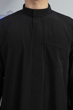 Qamis saoudien al emad noir avec détail sur le col minimaliste