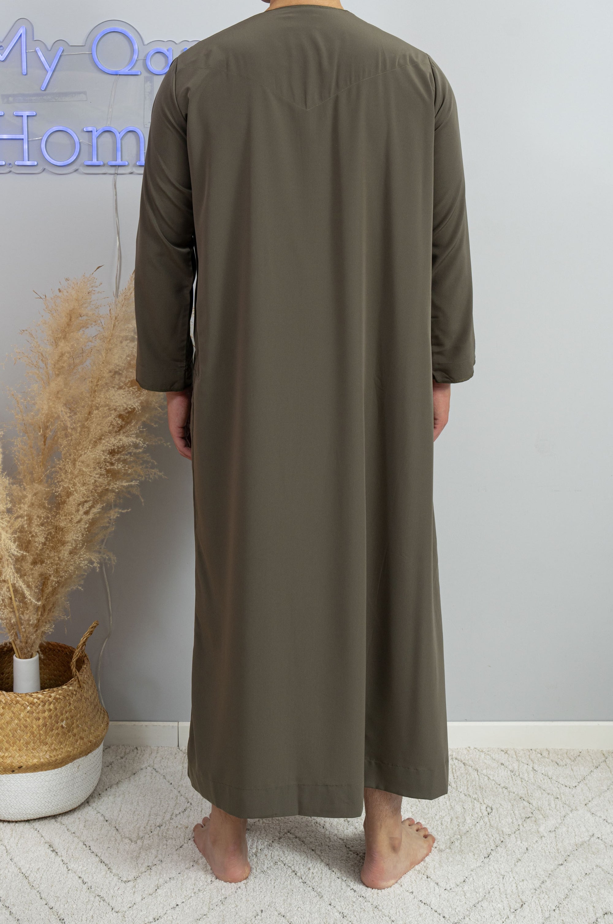 Homme musulman qui porte un Qamis émirati Dubai al emad kaki de dos