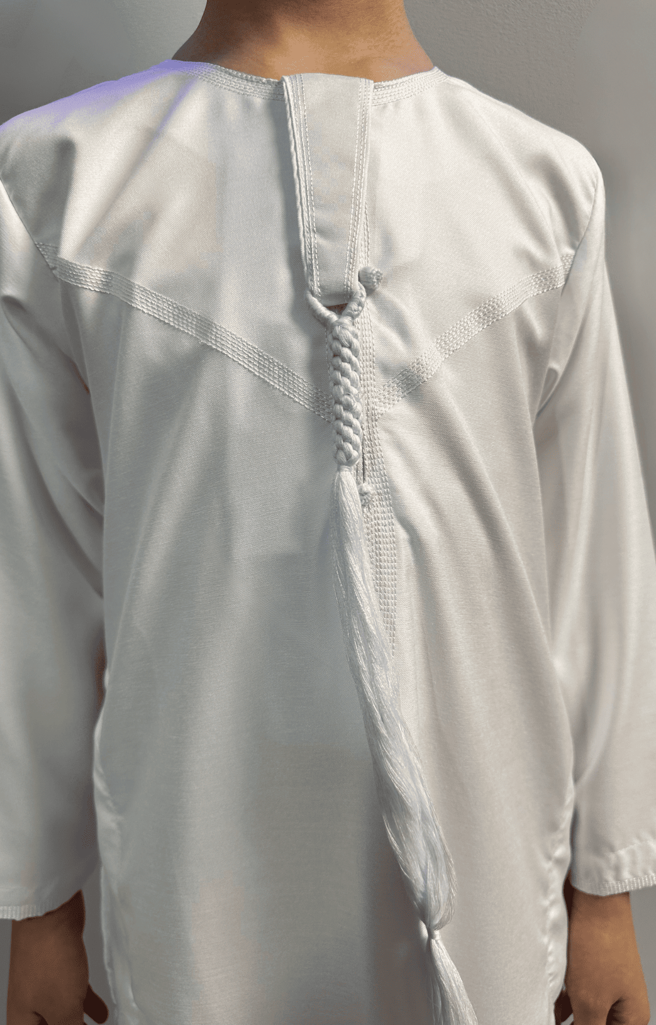 Garçon musulman portant un qamis enfant émirati al emad blanc détail sur le cravate