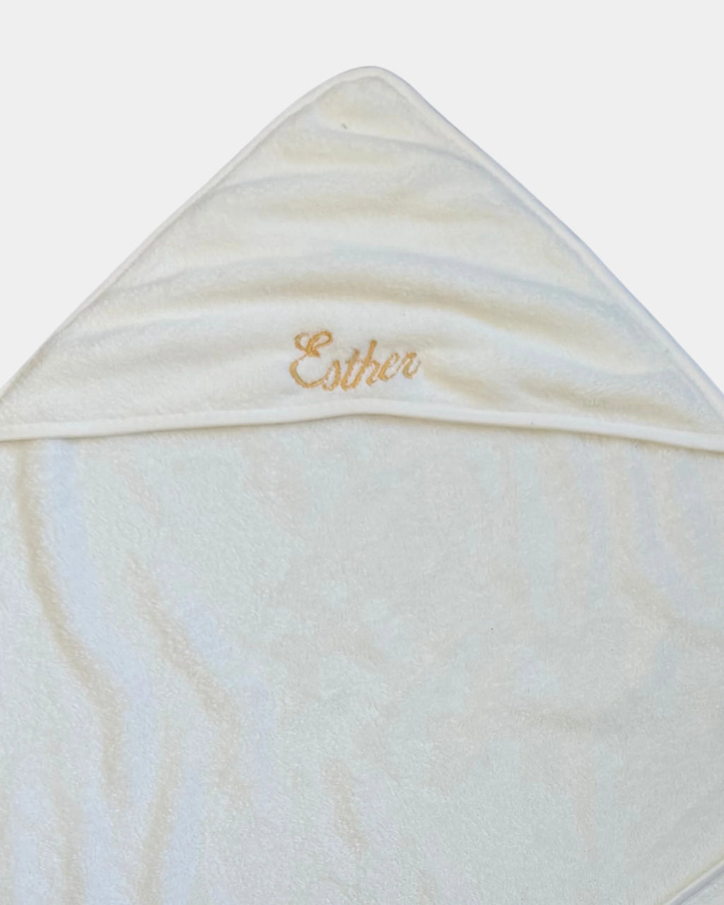 Détail de la broderie du prénom en fil doré sur la capuche de la serviette de bain bébé
