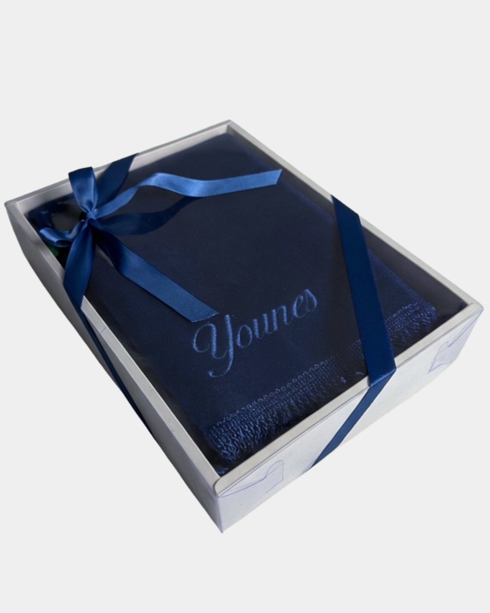 Tapis de prière en velours bleu marine avec le prénom Younes brodé en fil bleu clair, présenté dans un coffret cadeau blanc noué d'un ruban bleu marine assorti