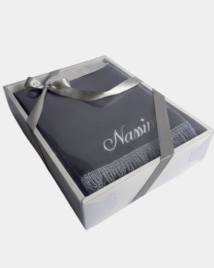 Tapis de prière en velours gris anthracite avec le prénom Nassim brodé en fil argenté, présenté dans un coffret cadeau blanc noué d'un ruban gris assorti