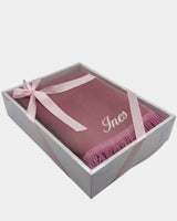 Tapis de prière en velours rose avec le prénom Ines brodé en fil blanc, présenté dans un coffret cadeau blanc noué d'un ruban rose assorti