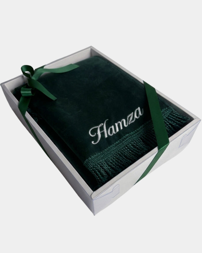 Tapis de prière en velours vert sapin avec le prénom Hamza brodé en fil blanc, présenté dans un coffret cadeau blanc noué d'un ruban vert assorti