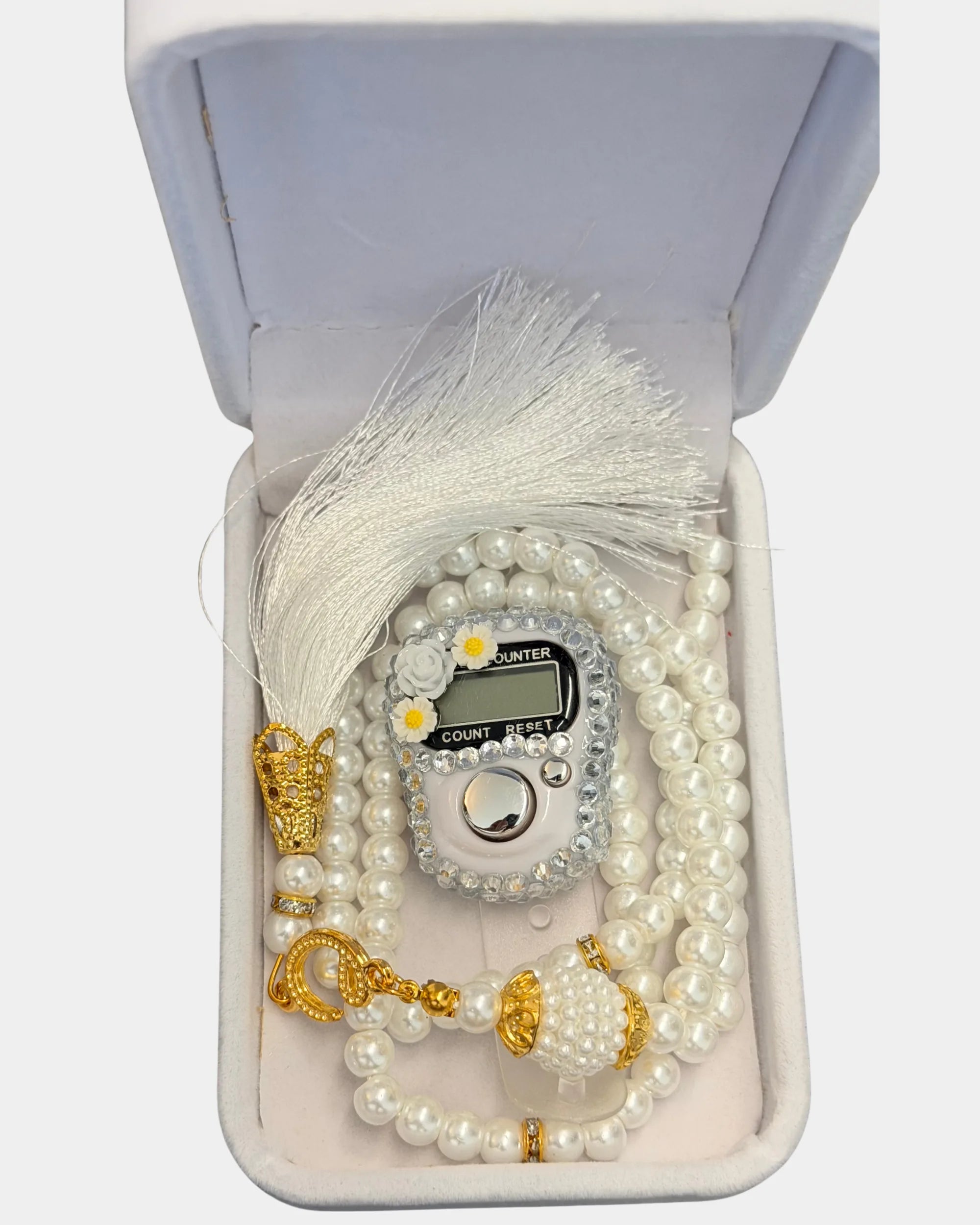 Gros plan du tasbih en perles blanches, compteur digital serti de strass et de fleurs, fermoirs dores et pompon en soie blanche